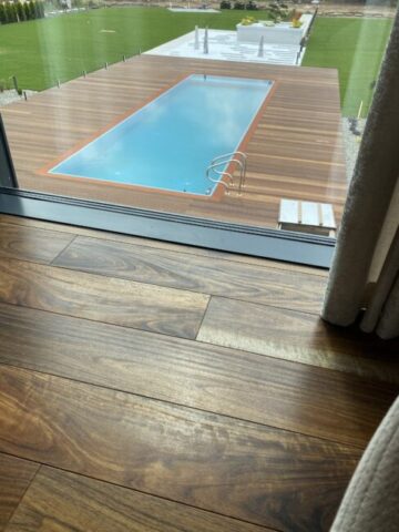 Podłoga z drewna egzotycznego amazouke przy dużym przeszkleniu z widokiem na taras i basen